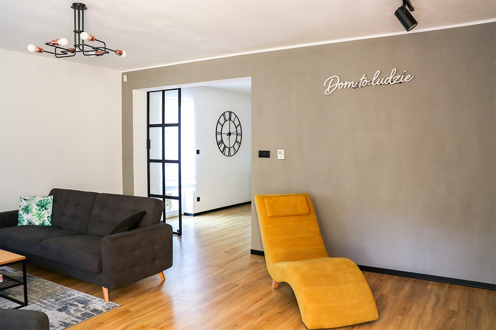 open living room, gray sofa in the living room, industrial lamp in the living room, yellow armchair for the living room, gray wall in the living room, living room open to the dining room, metal door with glass, sliding door with glass, loft style door, neon sign on the wall, neon decorations