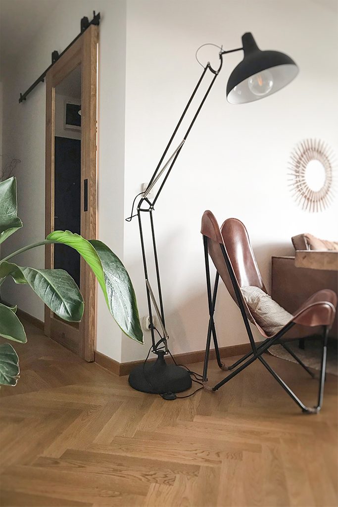 sliding door to office, wooden door with mirror, sliding door with mirror, large metal standing lamp, leather armchair on a metal base, vintage armchair, parquet floor in the living room, mirror in the hallway