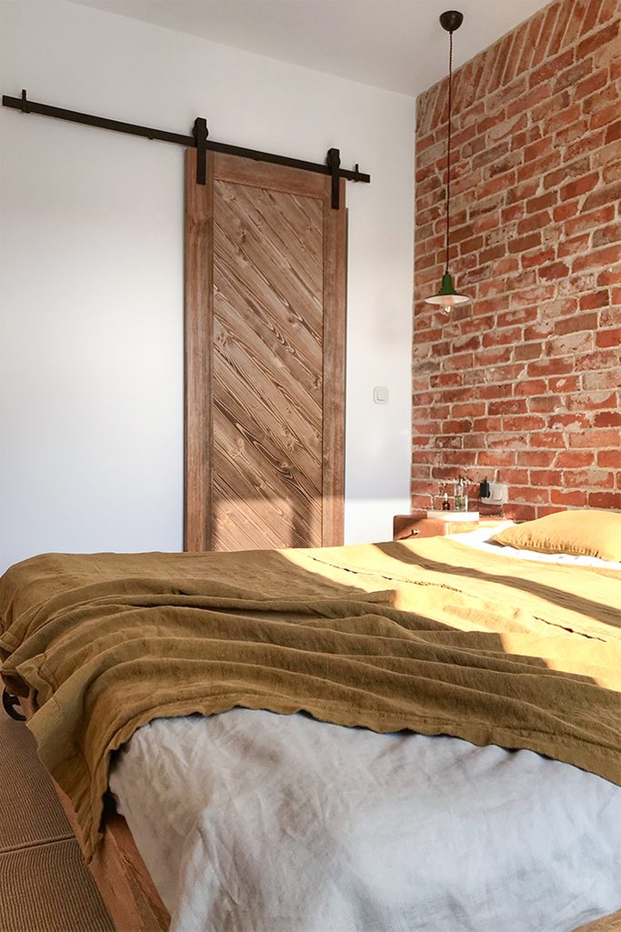 wooden sliding door, brick on the wall in the bedroom, sliding door to the wardrobe, bedroom with wardrobe, bedroom in loft style, metal hanging lamp for the bedroom