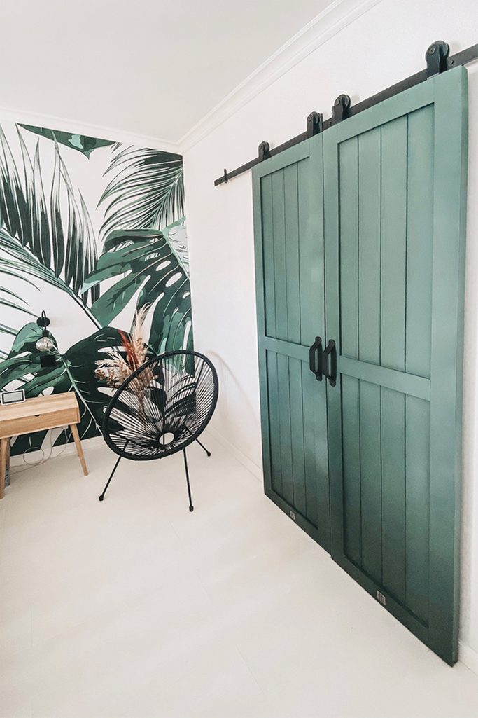 green doors, wardrobe door, green sliding door, solid wood colour door, decorative plant wallpaper, green bedroom wallpaper, black openwork chair, light wooden bedside table