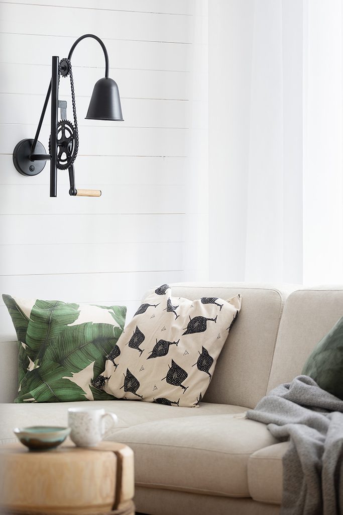 black industrial lamp on white wall, light brown sofa, decorative cushions